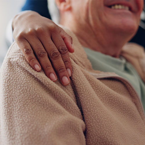 Lächelnder Senior mit Hand auf Schulter – Geborgenheit und Vertrauen in der Pflege